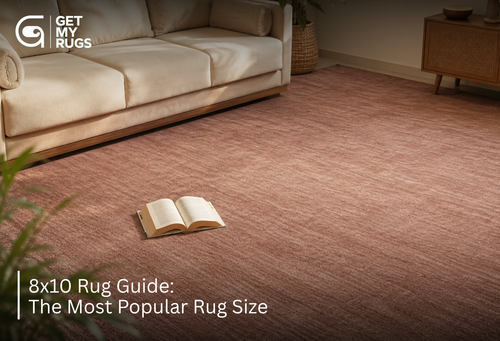Dusty rose 8x10 area rug extending beyond a cream sofa in a living room, with an open book resting on the rug