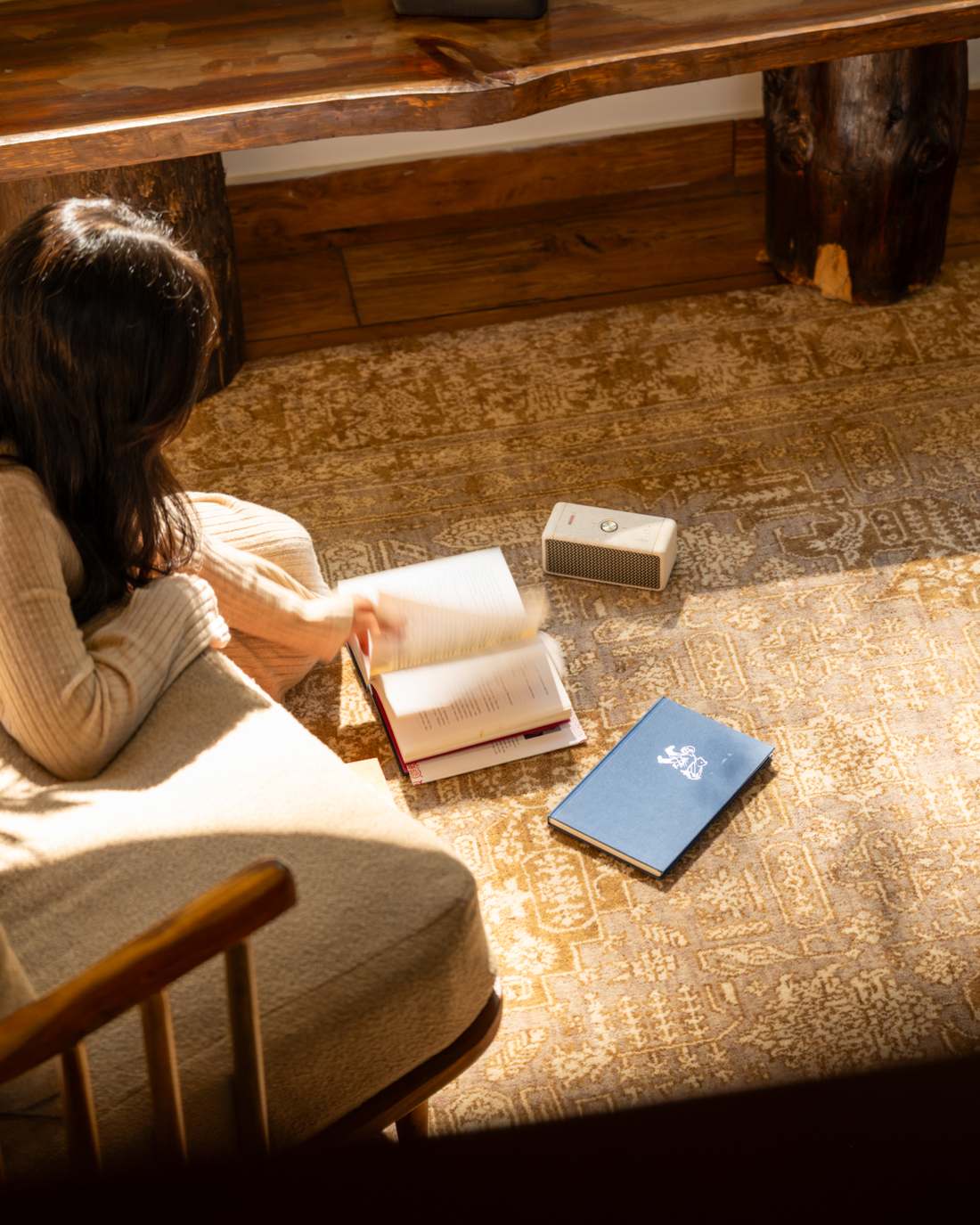 Woman reading by warm light on a hand-knotted gold-and-cream area rug